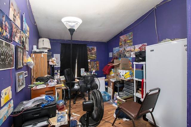 home office featuring hardwood / wood-style floors, lofted ceiling, and a textured ceiling