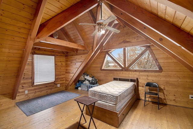 bedroom with lofted ceiling with beams, wood walls, and light hardwood / wood-style floors