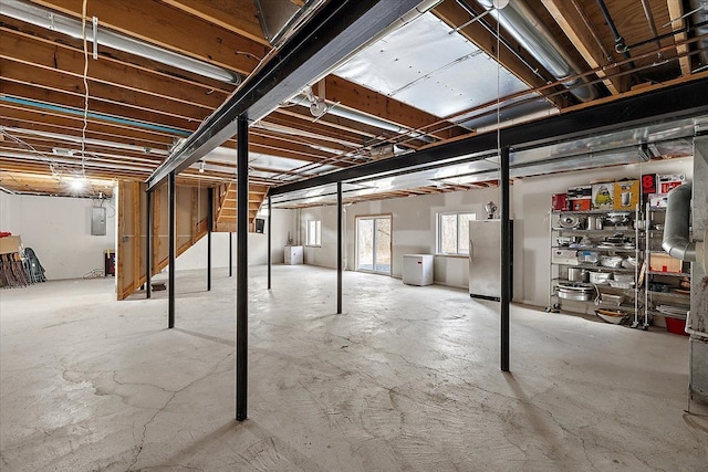 basement featuring electric panel and stainless steel refrigerator