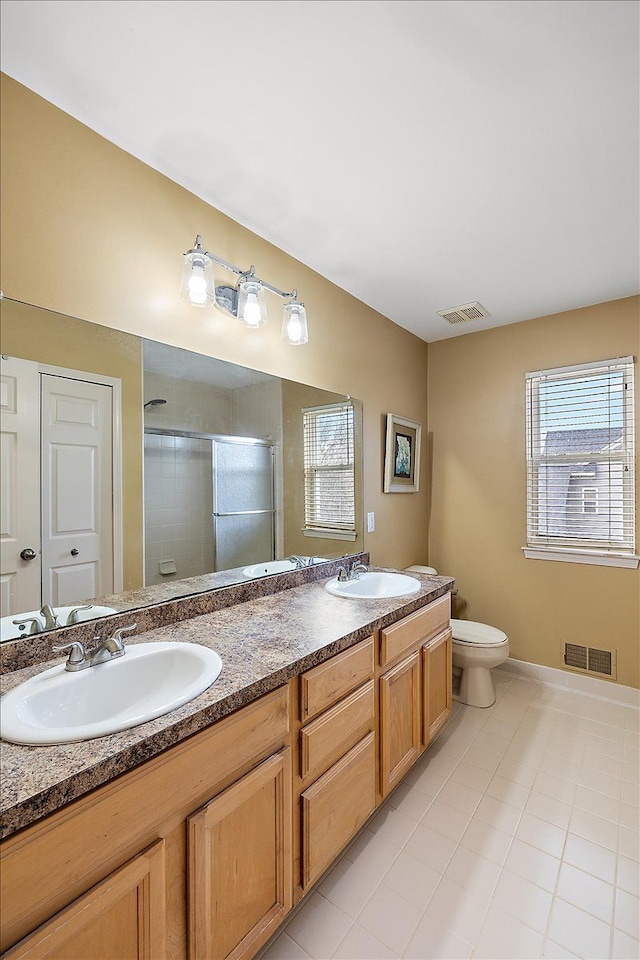 bathroom with tile patterned flooring, vanity, toilet, and an enclosed shower