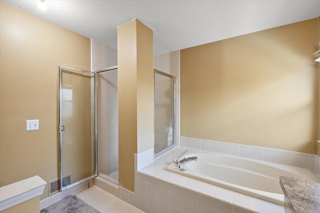 bathroom featuring plus walk in shower, vanity, and tile patterned flooring