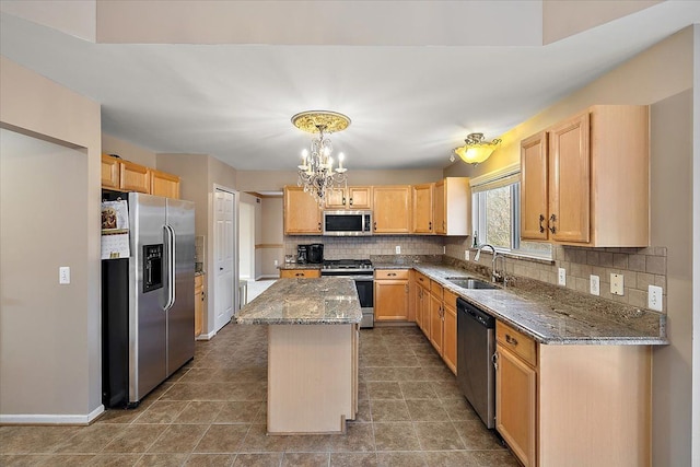 kitchen with dark stone countertops, a center island, sink, and stainless steel appliances