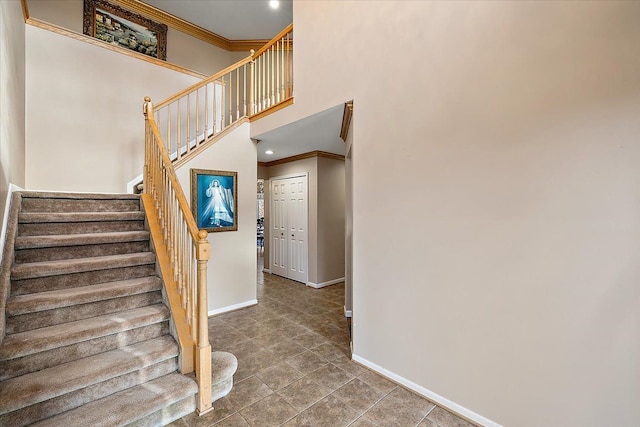 stairs with tile patterned floors, a towering ceiling, and crown molding