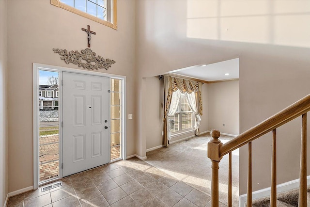 entrance foyer featuring light tile patterned floors, a towering ceiling, and crown molding