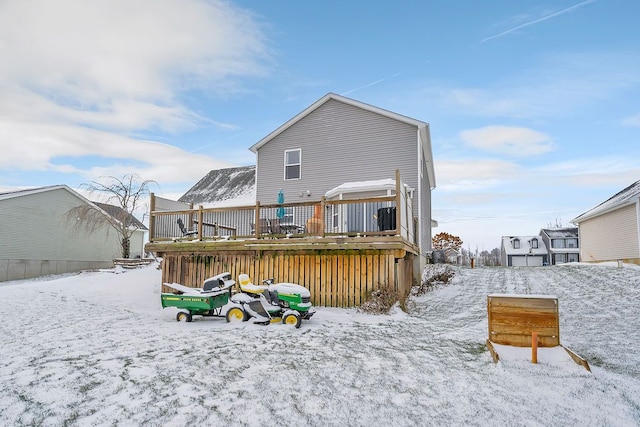 snow covered back of property featuring a deck