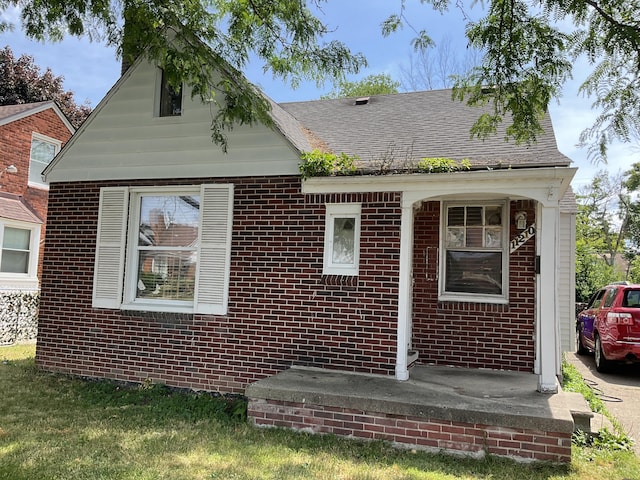 view of front of home featuring brick siding and roof with shingles