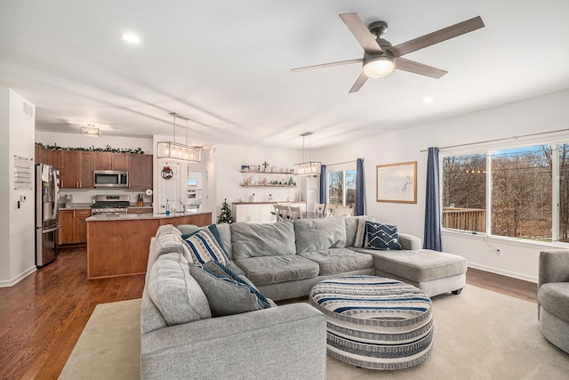 living room with ceiling fan with notable chandelier and dark hardwood / wood-style floors