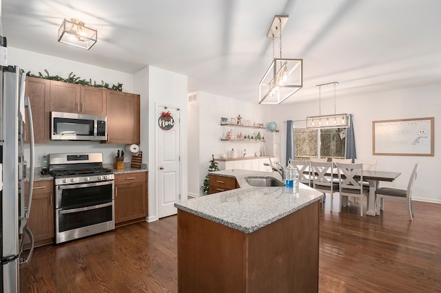 kitchen featuring sink, stainless steel appliances, dark hardwood / wood-style flooring, pendant lighting, and a kitchen island with sink