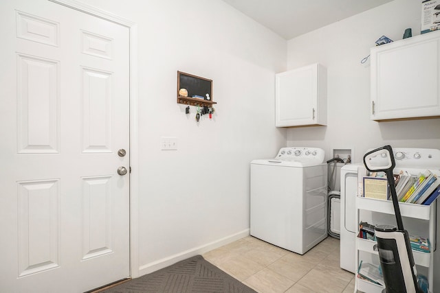 clothes washing area with cabinets, independent washer and dryer, and light tile patterned floors