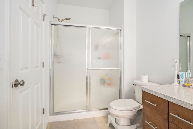 bathroom with tile patterned floors, vanity, a shower with shower door, and toilet