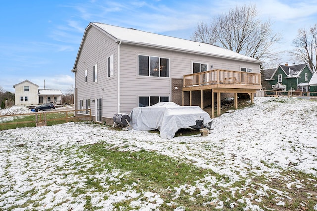 snow covered rear of property with a wooden deck