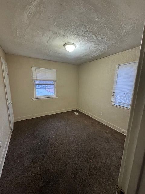 unfurnished bedroom featuring dark carpet and a textured ceiling