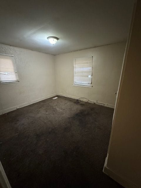 spare room featuring dark colored carpet