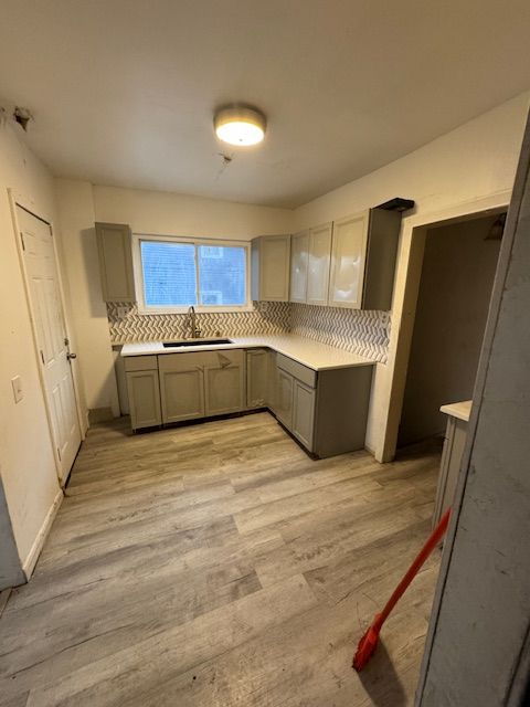 kitchen with gray cabinets, light hardwood / wood-style floors, sink, and tasteful backsplash