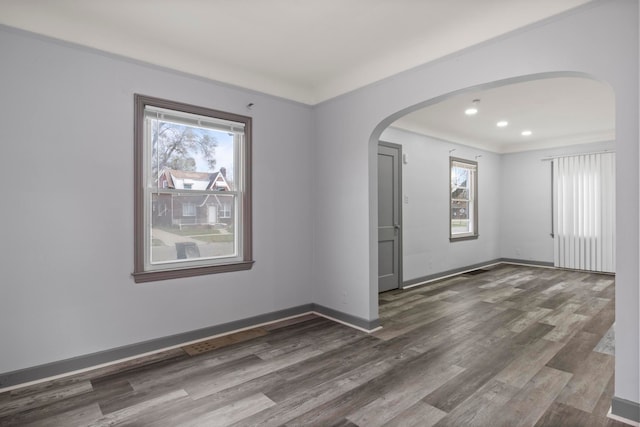 empty room featuring dark hardwood / wood-style floors, a wealth of natural light, and crown molding