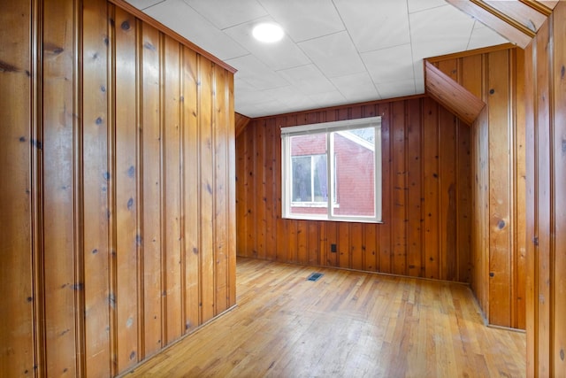 additional living space with wooden walls and light hardwood / wood-style flooring