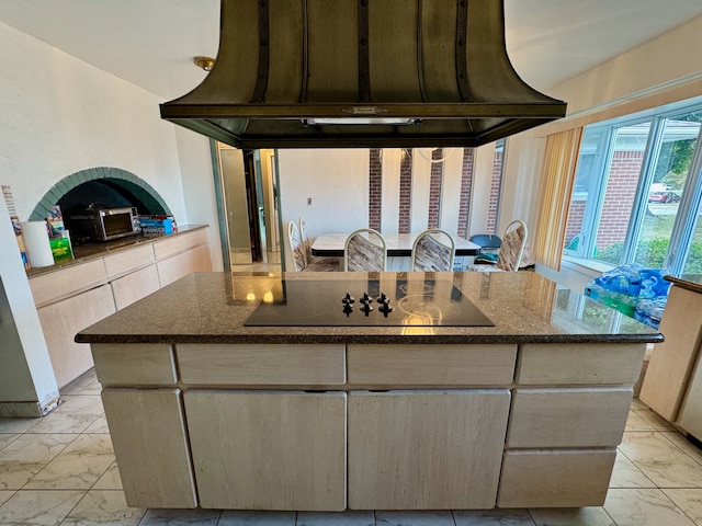 kitchen with custom range hood, a center island, black electric cooktop, and dark stone counters