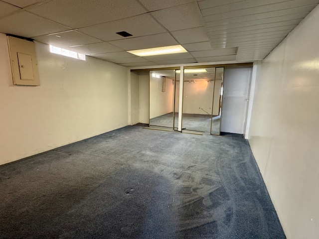 basement with electric panel, a drop ceiling, and carpet