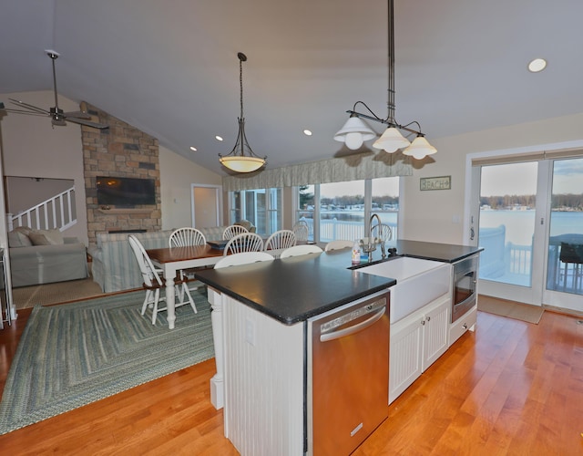 kitchen featuring stainless steel dishwasher, a healthy amount of sunlight, a water view, and white cabinetry