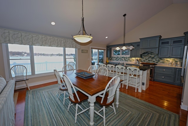 dining area with dark hardwood / wood-style flooring, a water view, high vaulted ceiling, and sink