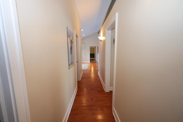 corridor with dark hardwood / wood-style flooring and lofted ceiling