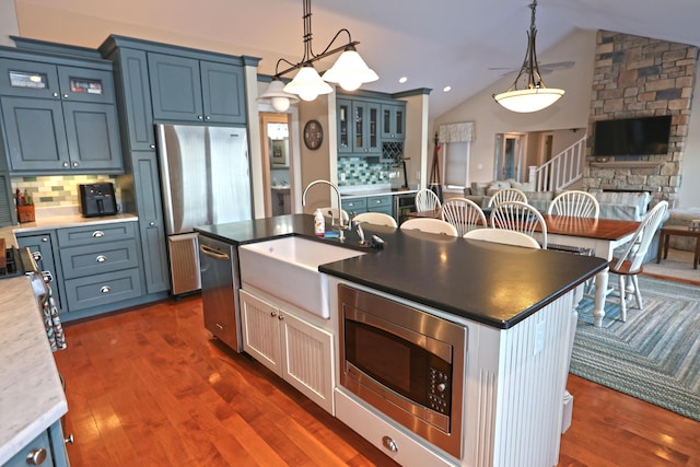 kitchen with dark hardwood / wood-style flooring, lofted ceiling, stainless steel appliances, and tasteful backsplash