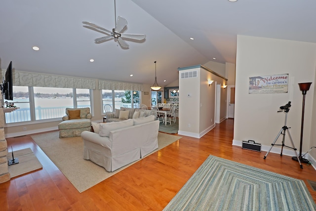 living room featuring ceiling fan, a water view, light wood-type flooring, and vaulted ceiling