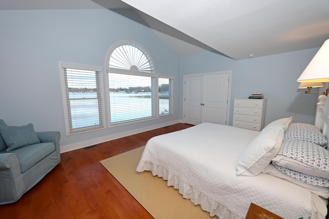 bedroom with a closet, dark hardwood / wood-style flooring, and vaulted ceiling