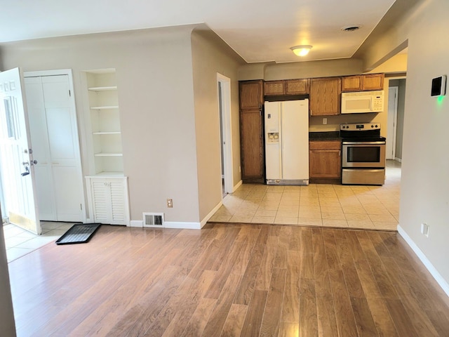 kitchen featuring built in features, white appliances, and light hardwood / wood-style flooring