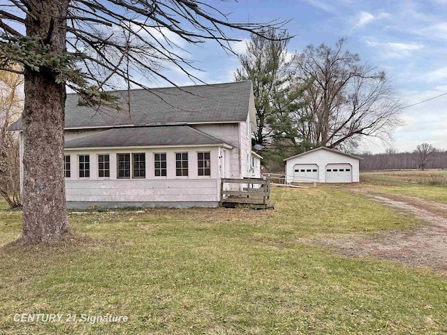 view of home's exterior with a garage, a yard, and an outbuilding