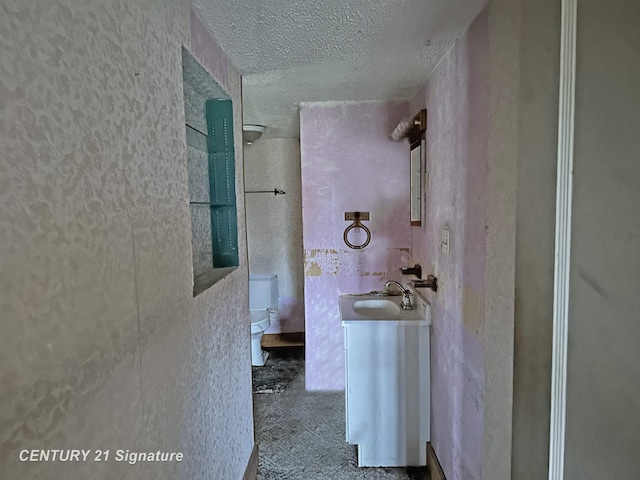 bathroom with a textured ceiling, vanity, and toilet