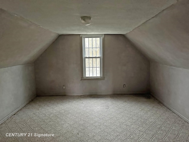 bonus room with light colored carpet and vaulted ceiling