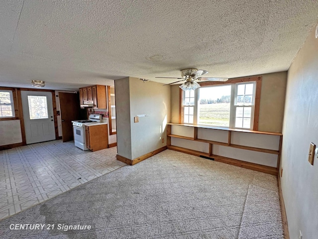 kitchen featuring a textured ceiling, light colored carpet, ceiling fan, and gas range gas stove