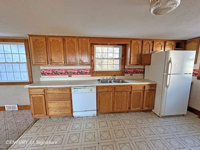 kitchen featuring a textured ceiling, white appliances, and sink