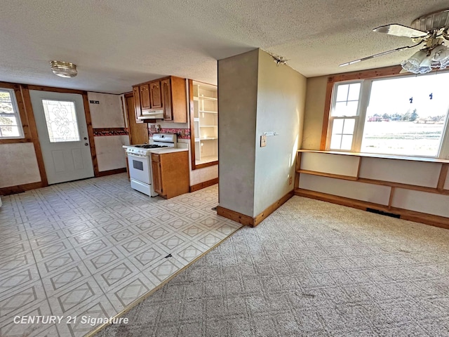 kitchen with kitchen peninsula, ceiling fan, white gas stove, and a textured ceiling