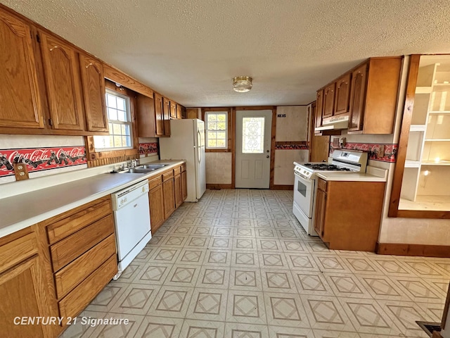 kitchen featuring a textured ceiling, white appliances, and sink