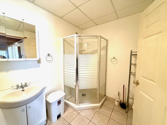 bathroom with tile patterned flooring, vanity, a shower with shower door, and a drop ceiling