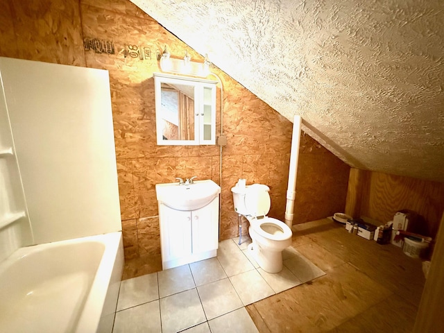 bathroom featuring vaulted ceiling, tile patterned flooring, vanity, toilet, and a textured ceiling