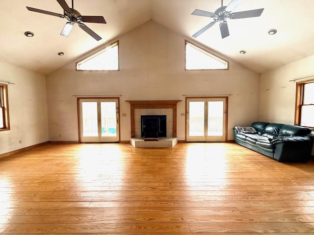 unfurnished living room with french doors, ceiling fan, a fireplace, and light hardwood / wood-style floors