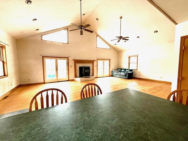 unfurnished dining area with ceiling fan, light hardwood / wood-style flooring, high vaulted ceiling, and a healthy amount of sunlight