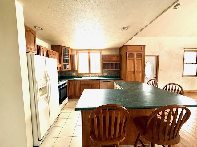 kitchen with sink, tasteful backsplash, a textured ceiling, a kitchen island, and white appliances