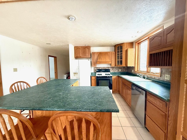 kitchen featuring sink, light tile patterned floors, stainless steel dishwasher, range with gas stovetop, and white fridge with ice dispenser