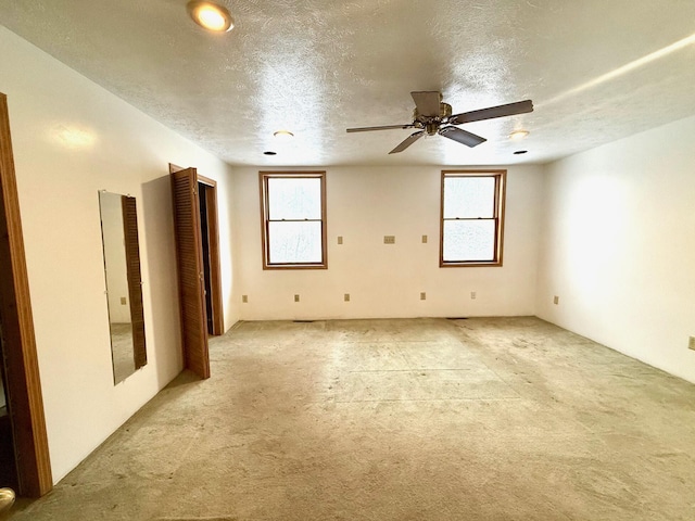 empty room with ceiling fan and a textured ceiling