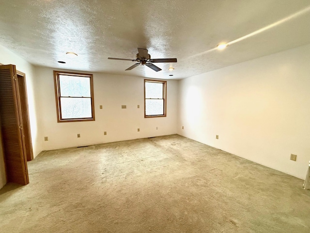 carpeted spare room with ceiling fan and a textured ceiling