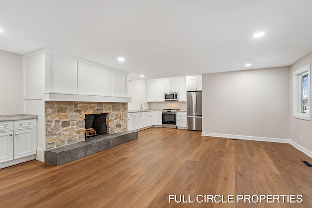 unfurnished living room featuring a fireplace, light wood-type flooring, and sink