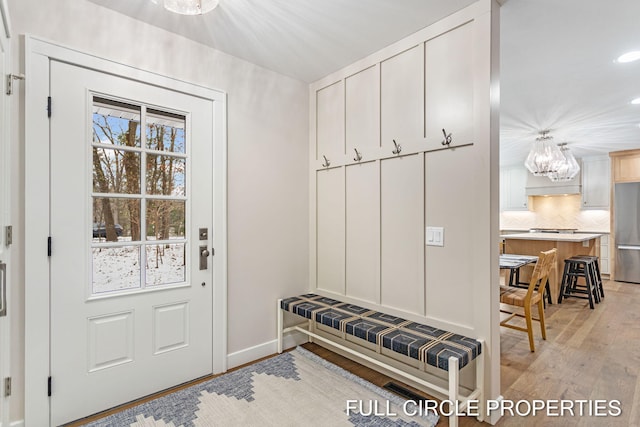 mudroom with light hardwood / wood-style flooring and a notable chandelier