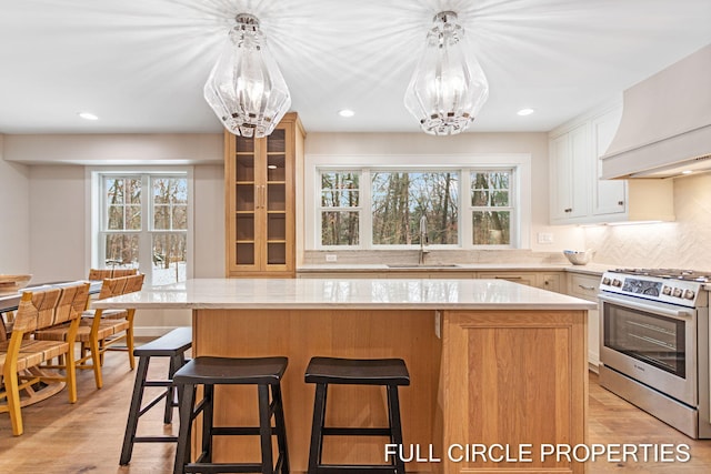 kitchen with white cabinets, a center island, sink, and stainless steel range