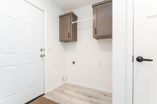 laundry area with hookup for an electric dryer, light hardwood / wood-style flooring, and cabinets