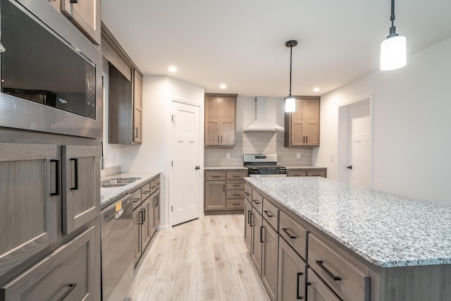 kitchen featuring hanging light fixtures, stainless steel appliances, light wood-type flooring, and custom exhaust hood