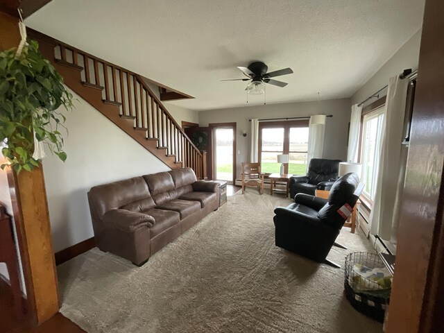 carpeted living room with ceiling fan and a textured ceiling